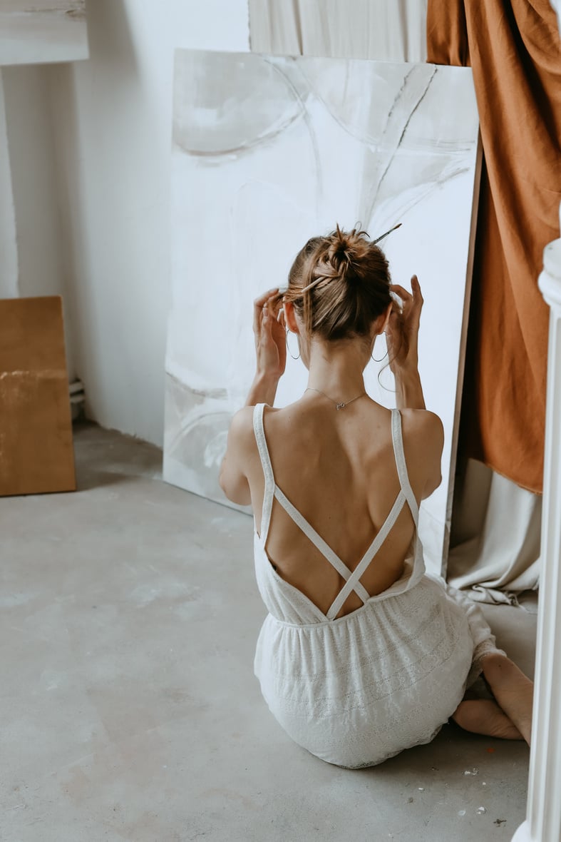 Back View of a Woman in White Dress Sitting on the Floor